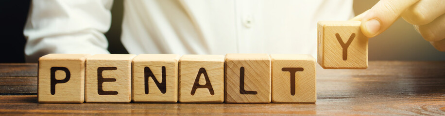 Hand stacking wooden cubes to spell 'penalty'